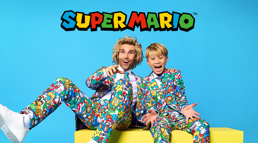 Two people in colorful Super Mario-themed suits sitting on a yellow couch with the Super Mario logo above.